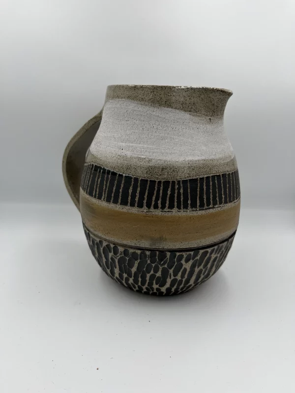 Pichet aux tons natures divisé en 5 sections, beige, blanc, noir avec lignes verticale, moucheté texturisé noir et brut.